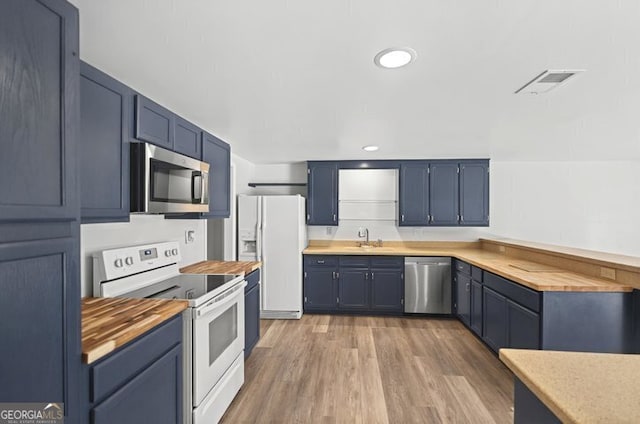 kitchen featuring wood counters, a sink, appliances with stainless steel finishes, visible vents, and wood finished floors
