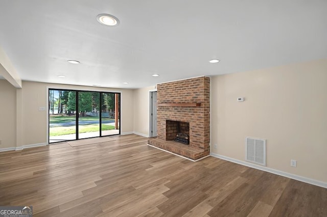 unfurnished living room featuring baseboards, visible vents, wood finished floors, and a fireplace