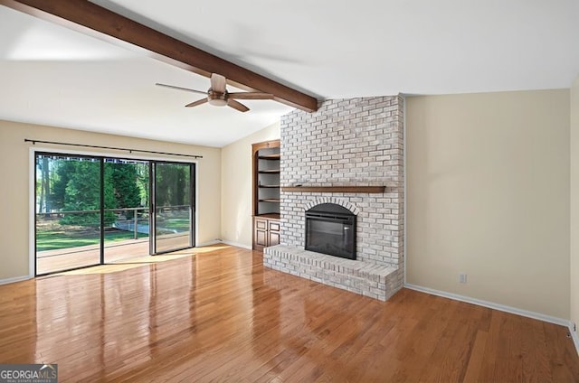 unfurnished living room featuring ceiling fan, lofted ceiling with beams, baseboards, a brick fireplace, and wood finished floors
