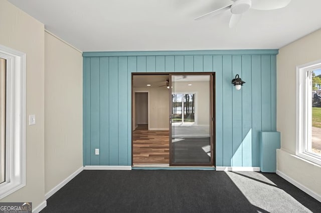 carpeted empty room featuring ceiling fan and baseboards