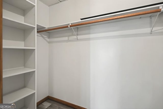 walk in closet with dark wood-style floors