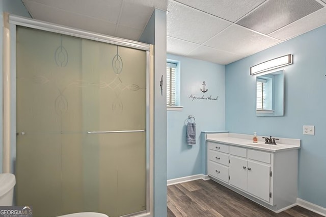 full bathroom featuring baseboards, wood finished floors, a shower stall, and toilet
