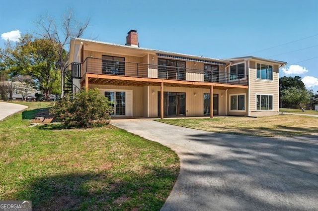 view of front of house with a front lawn, driveway, and a chimney