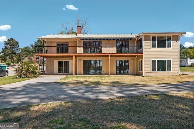 view of front of home featuring a chimney, metal roof, and a front yard