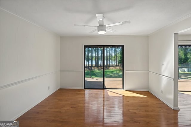 spare room with ornamental molding, a ceiling fan, wood finished floors, and baseboards
