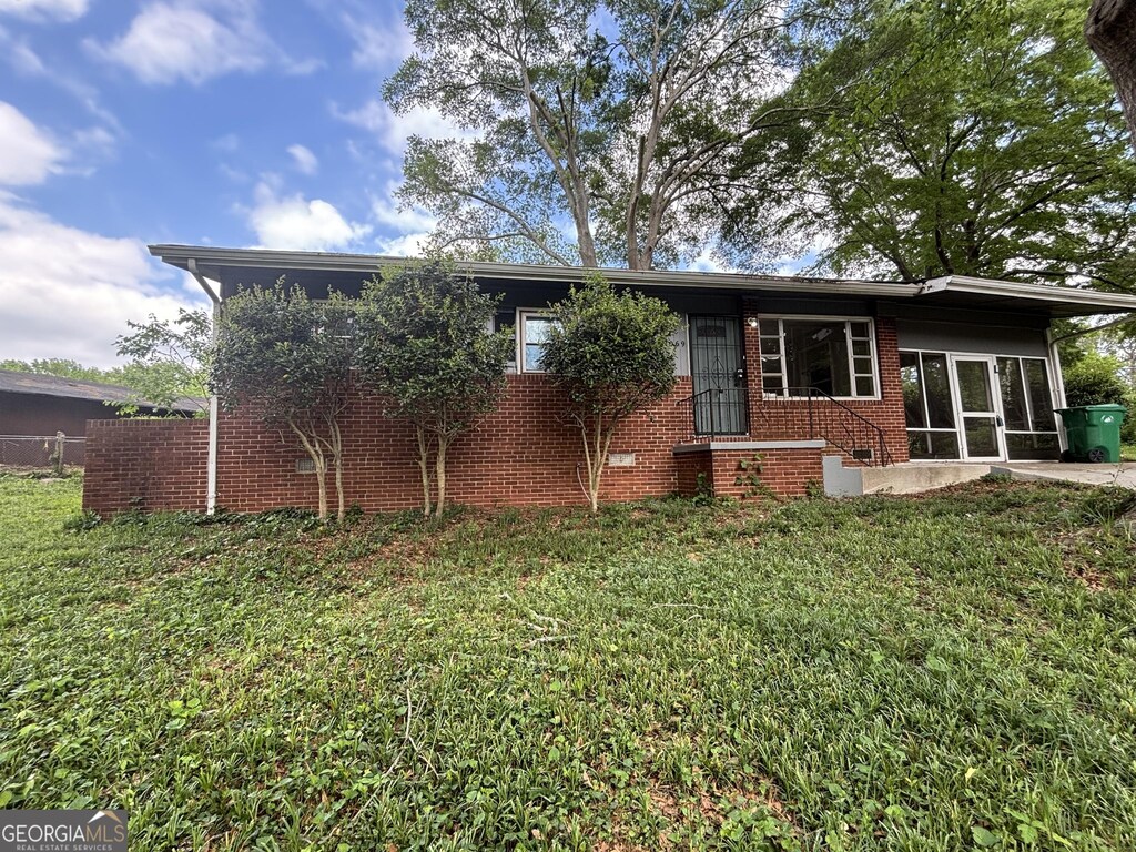 2069 Bixler Cir, Decatur, GA 30032 - rear view of property featuring brick siding, fence, a sunroom, crawl space, and a lawn