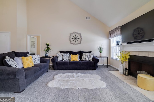 living room with carpet flooring, visible vents, baseboards, a fireplace, and high vaulted ceiling