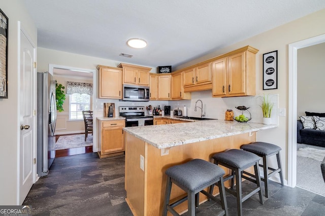 kitchen featuring a sink, appliances with stainless steel finishes, visible vents, light countertops, and a peninsula