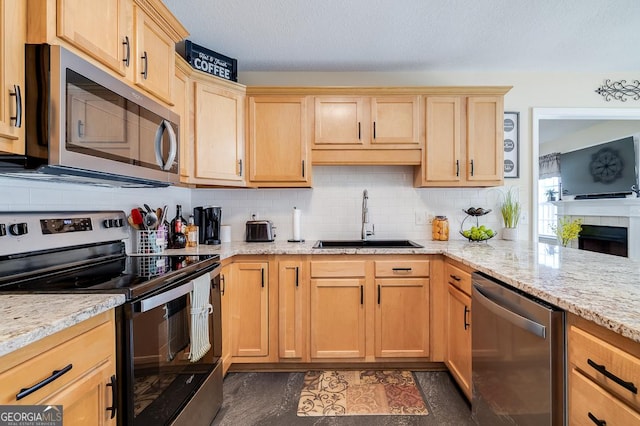 kitchen featuring light brown cabinetry, a sink, stainless steel appliances, and decorative backsplash