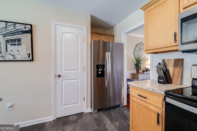 kitchen featuring light brown cabinets, light stone counters, appliances with stainless steel finishes, backsplash, and baseboards