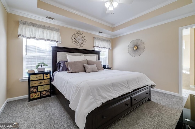 carpeted bedroom featuring ornamental molding, visible vents, baseboards, and a tray ceiling