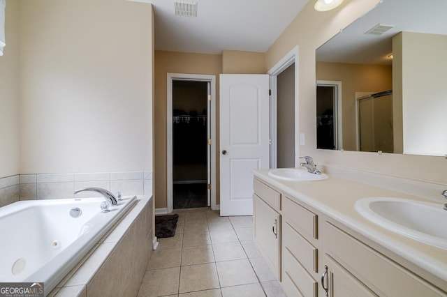 bathroom featuring a walk in closet, visible vents, a whirlpool tub, and a sink