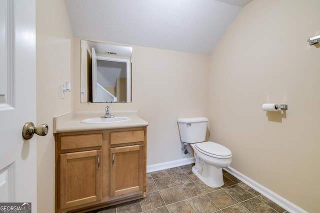 bathroom with lofted ceiling, visible vents, baseboards, toilet, and vanity