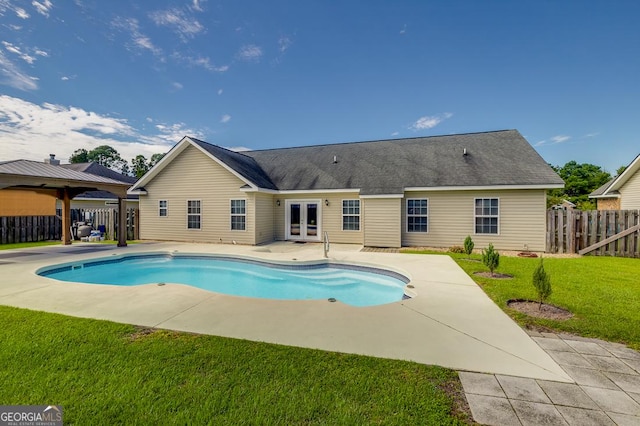 view of swimming pool featuring a yard, fence, a fenced in pool, a patio area, and french doors