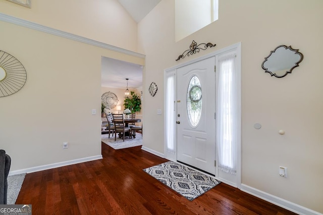 foyer with high vaulted ceiling, wood finished floors, and baseboards