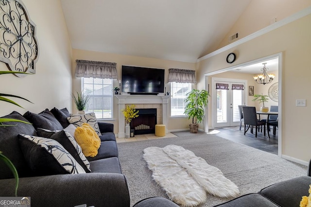 living area with an inviting chandelier, a tiled fireplace, high vaulted ceiling, visible vents, and baseboards