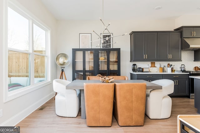 dining area with a notable chandelier, visible vents, light wood-style flooring, and baseboards