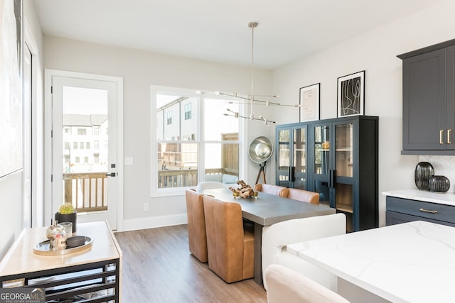dining room with an inviting chandelier, baseboards, and light wood-type flooring