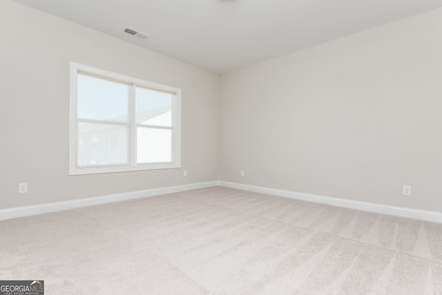 spare room featuring visible vents, light colored carpet, and baseboards