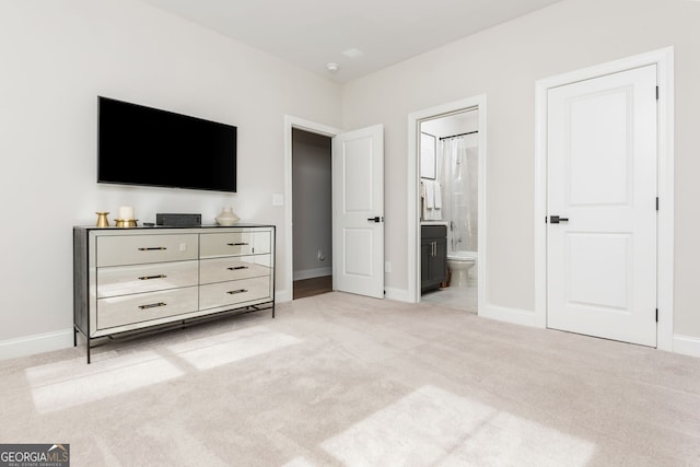 carpeted bedroom with ensuite bath and baseboards