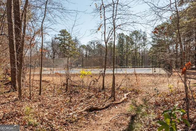view of yard with a tennis court and fence