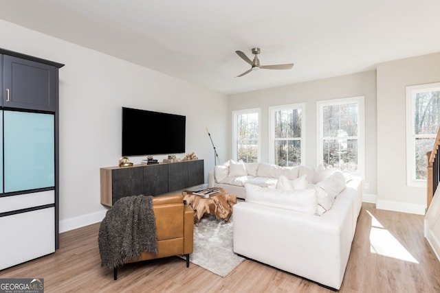 living room with baseboards, a ceiling fan, and light wood finished floors