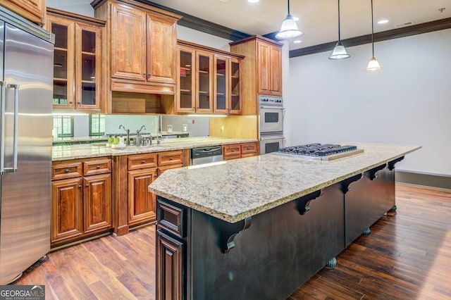 kitchen featuring light stone countertops, stainless steel appliances, a kitchen breakfast bar, and ornamental molding