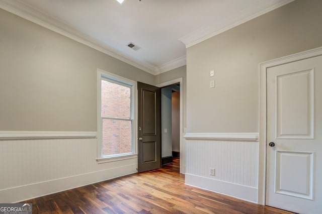 unfurnished room featuring visible vents, a wainscoted wall, and a healthy amount of sunlight