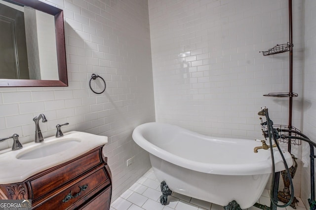 bathroom featuring tile walls, vanity, tile patterned flooring, and a freestanding bath