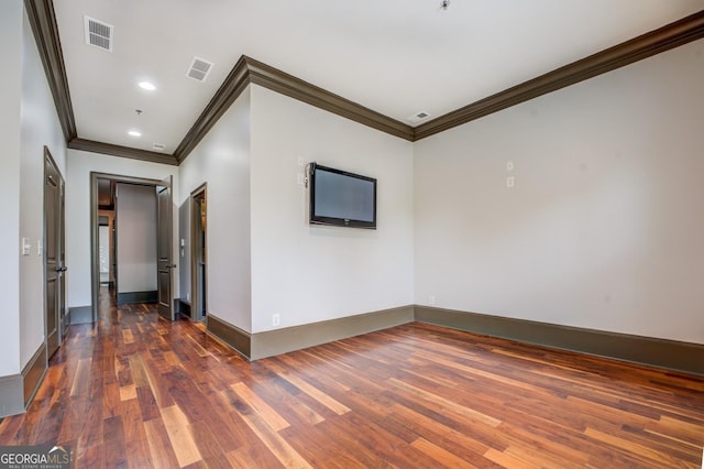 empty room featuring dark wood-style floors, visible vents, crown molding, and baseboards