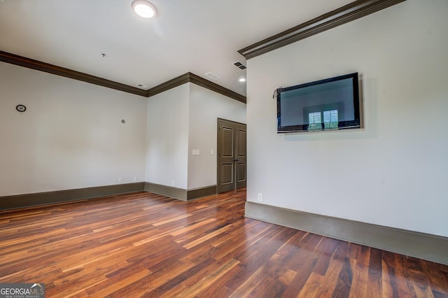 empty room with visible vents, baseboards, wood finished floors, and crown molding