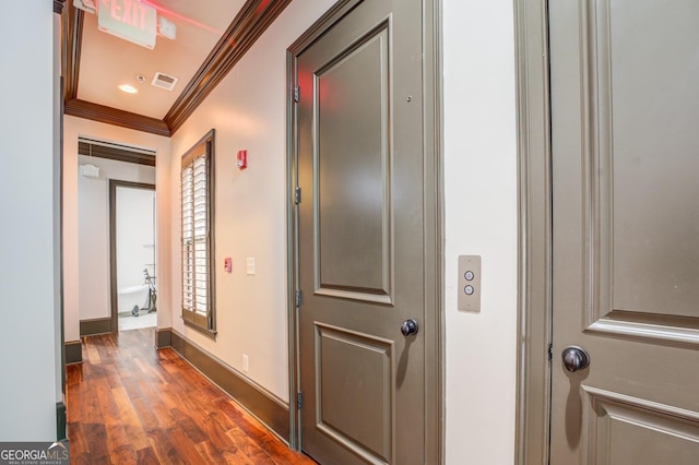hall featuring ornamental molding, visible vents, baseboards, and dark wood finished floors