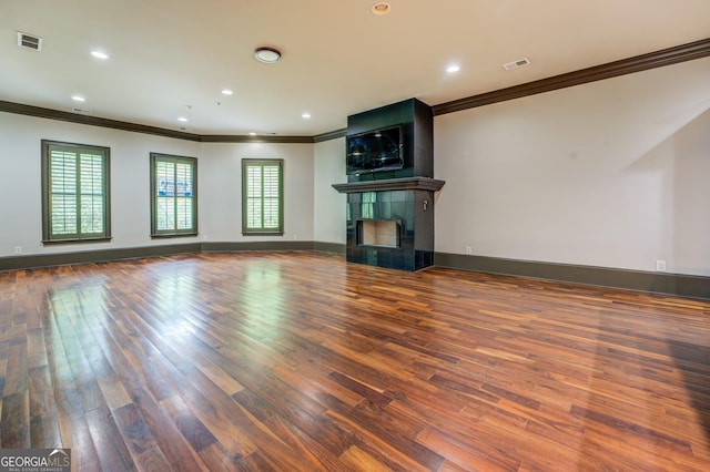 unfurnished living room featuring wood finished floors, visible vents, and ornamental molding