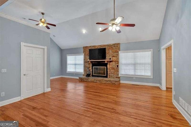 unfurnished living room with ceiling fan, vaulted ceiling, wood finished floors, and a fireplace
