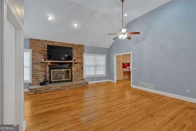 unfurnished living room with a fireplace, a ceiling fan, visible vents, baseboards, and wood finished floors