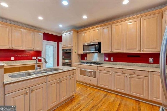kitchen featuring light brown cabinets, a warming drawer, appliances with stainless steel finishes, light countertops, and a sink