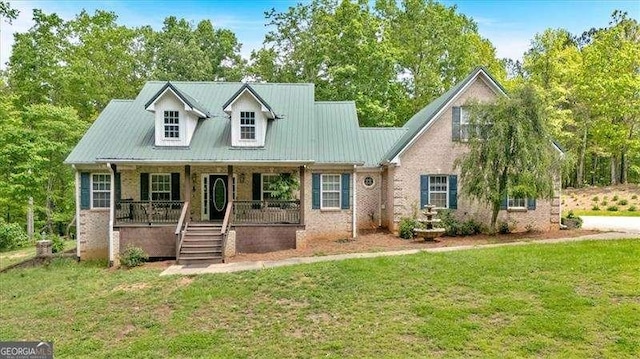 new england style home featuring a porch, a front lawn, and brick siding