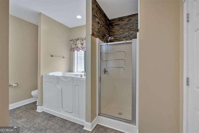 bathroom featuring toilet, a shower stall, and baseboards