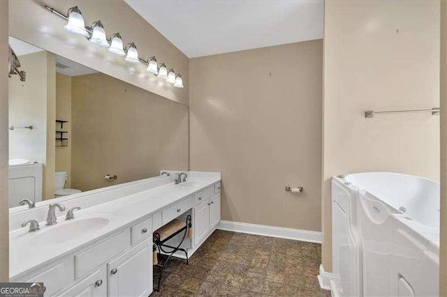 bathroom with double vanity, toilet, a bath, a sink, and baseboards