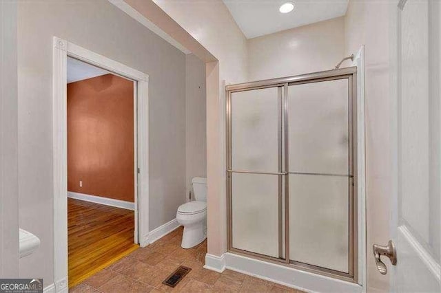 full bathroom featuring a shower with shower door, visible vents, toilet, and baseboards