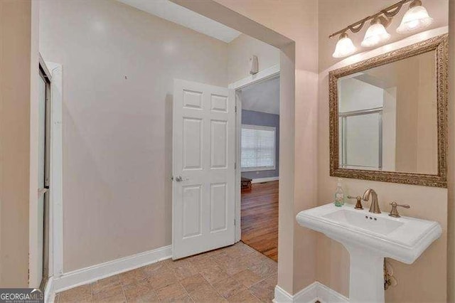 bathroom featuring baseboards, an enclosed shower, and a sink