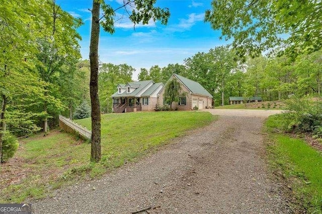 view of front of home with dirt driveway, a front lawn, and an attached garage