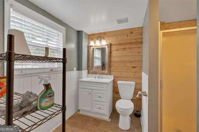 bathroom with visible vents, wood walls, toilet, and vanity