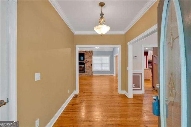 hall featuring baseboards, crown molding, and light wood-style flooring