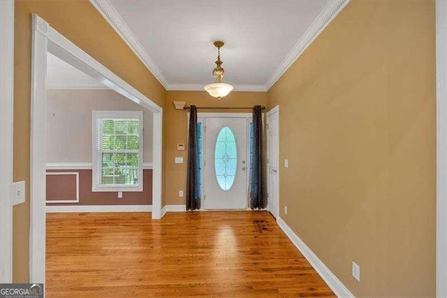 entrance foyer with wood finished floors, ornamental molding, and baseboards