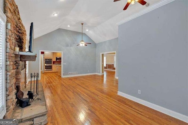 unfurnished living room featuring baseboards, light wood-type flooring, a ceiling fan, and high vaulted ceiling
