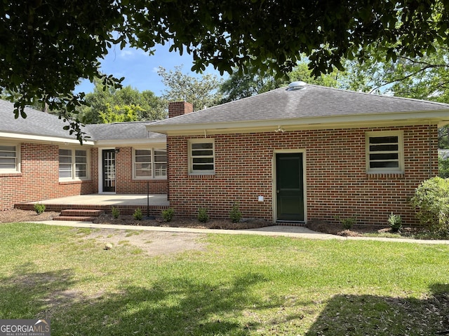 106 Zenith St, Dublin, GA 31021 - back of property featuring a shingled roof, a patio area, a yard, a chimney, and brick siding