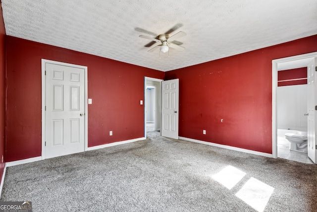 unfurnished bedroom with baseboards, ensuite bathroom, a textured ceiling, and carpet