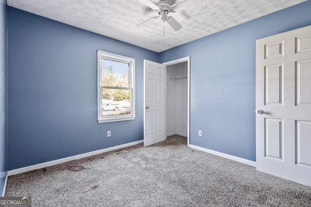 unfurnished bedroom featuring a textured ceiling, carpet flooring, visible vents, a closet, and baseboards
