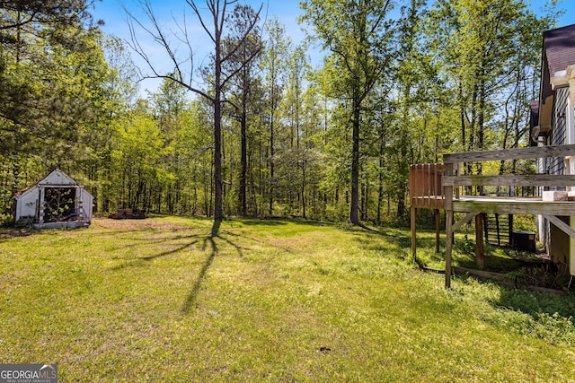 view of yard with an outdoor structure, stairs, a view of trees, and a wooden deck